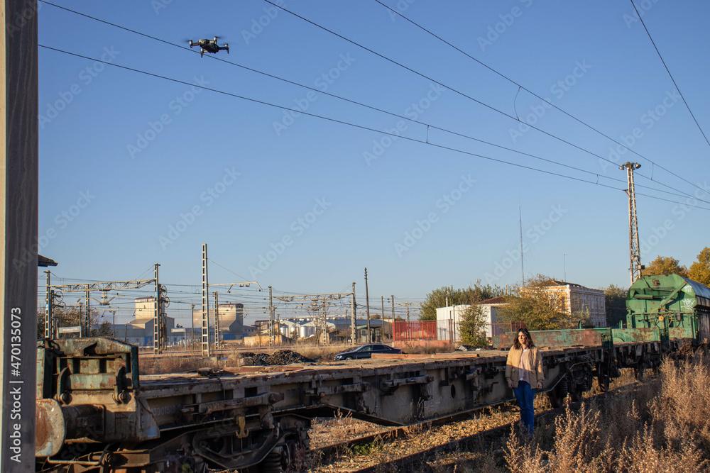 brunette and young model on railroad tracks next to scrapped old freight train and drone filming photo reportage brunette and young model on railroad tracks next to scrapped old freight train and drone filming photo reportage