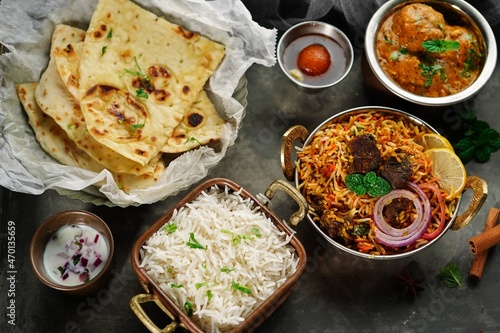 Indian meal thali - mutton biryani, raita, malai kofta, basmati rice, butter naan and gulab jamun served on a tray