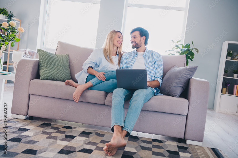 Full body photo of husband wife use laptop remote work self-isolation feelings support sit divan indoors Full body photo of husband wife use laptop remote work self-isolation feelings support sit divan indoors