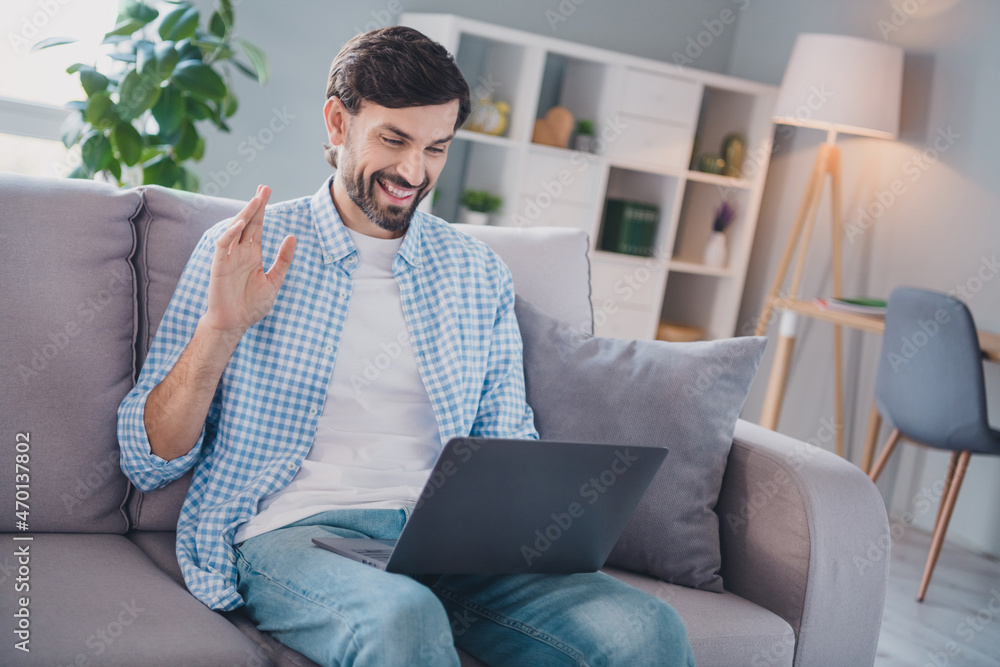 Photo of friendly cheerful man sit couch remote conference communication wear casual outfit in comfortable home indoors Photo of friendly cheerful man sit couch remote conference communication wear casual outfit in comfortable home indoors