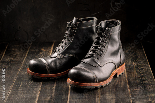 Hand crafted black leather high boots on wooden background