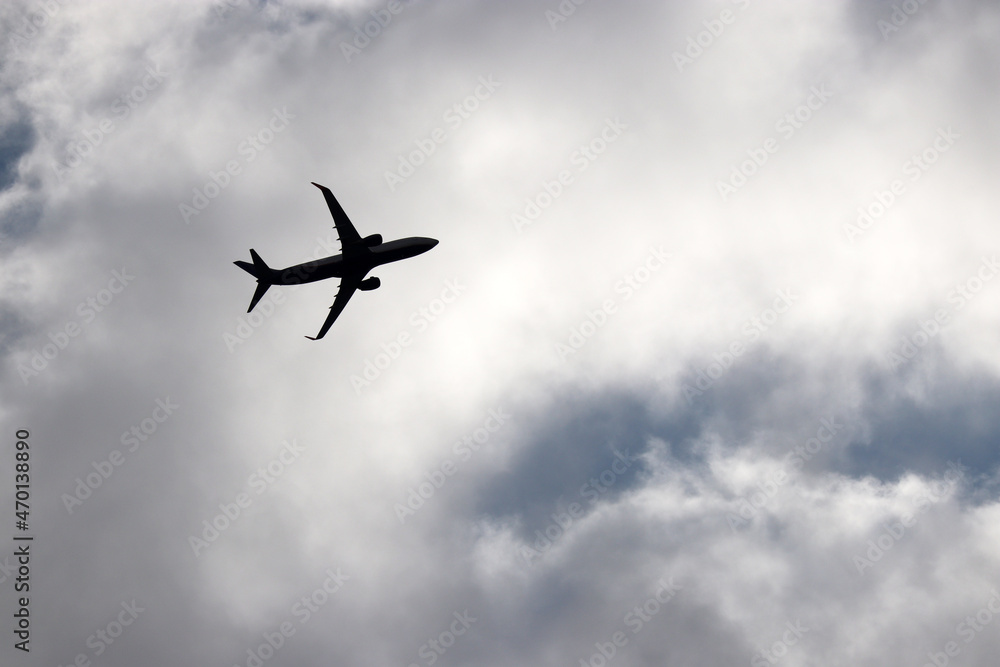 Silhouette of airplane flying in sky with white clouds. Passenger plane at flight, travel concept Silhouette of airplane flying in sky with white clouds. Passenger plane at flight, travel concept