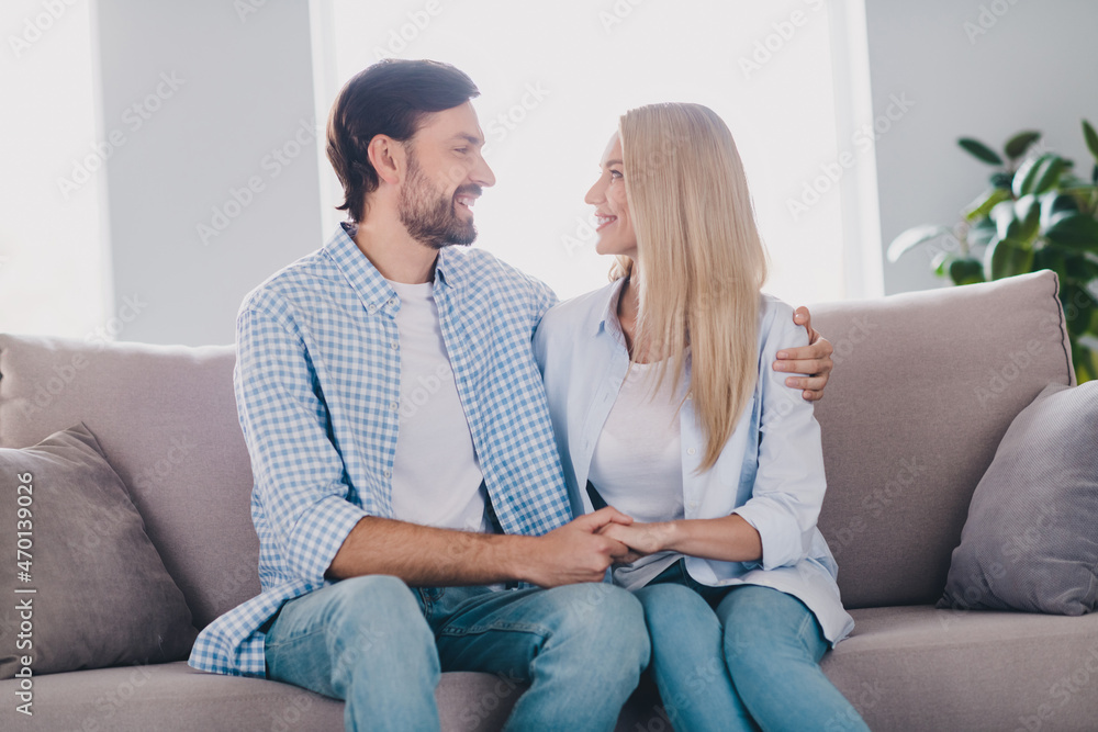 Photo of coquette young couple hug look brunet guy blond lady wear white shirt jeans in living room rest indoors Photo of coquette young couple hug look brunet guy blond lady wear white shirt jeans in living room rest indoors
