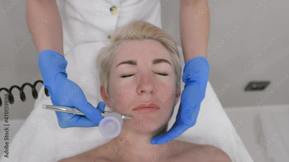 An adult woman receives a gas-liquid peeling procedure. Professional cosmetologist services. Top view An adult woman receives a gas-liquid peeling procedure. Professional cosmetologist services. Top view