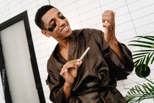 Black man with eye patches doing manicure with nail file