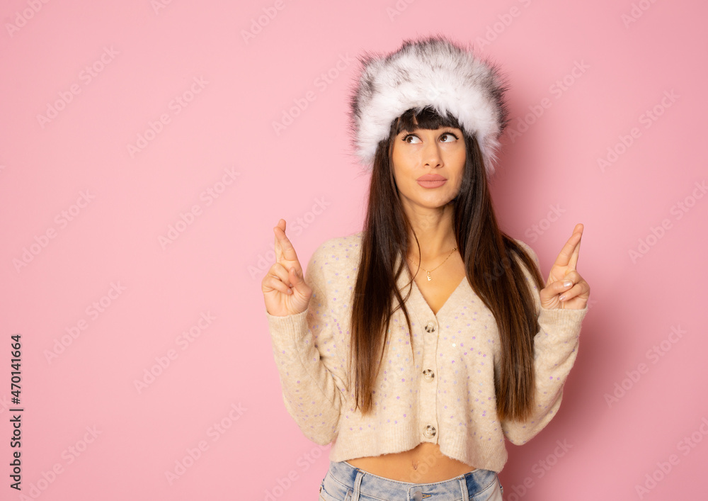 Naklejka premium Beautiful young woman with long hair in winter clothing pointing fingers up isolated over pink background.