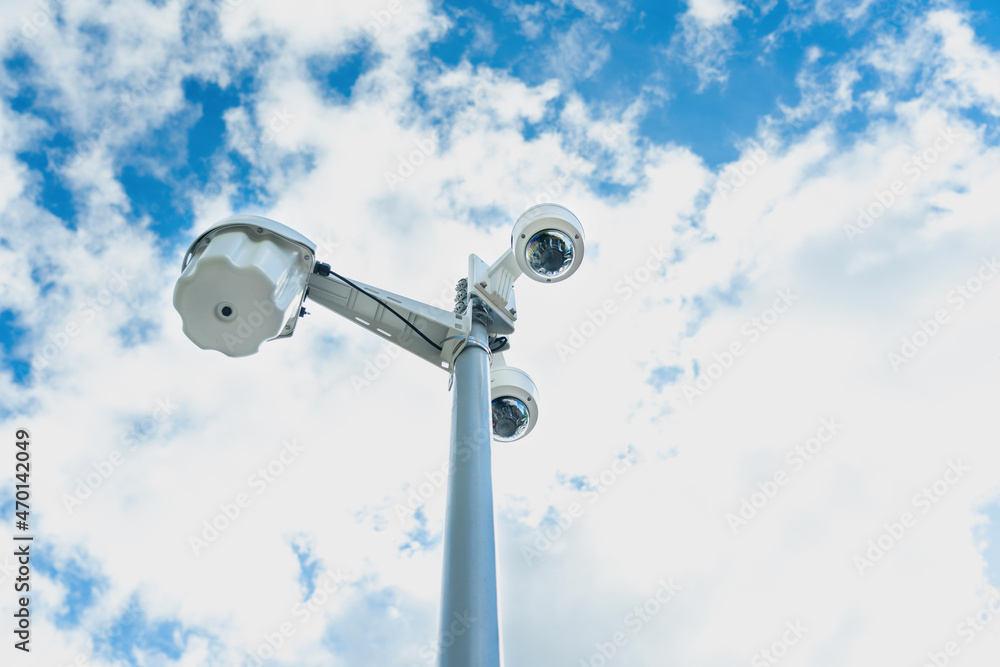 A group of CCTV cameras on a pole against the background of the sky with clouds. Horizontal photo