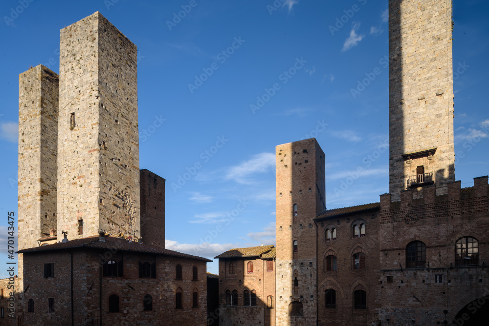 Geschlechtertürme, San Gimignano, Toskana, Italien bei Himmel mit Wolken und Sonne und Schatten.