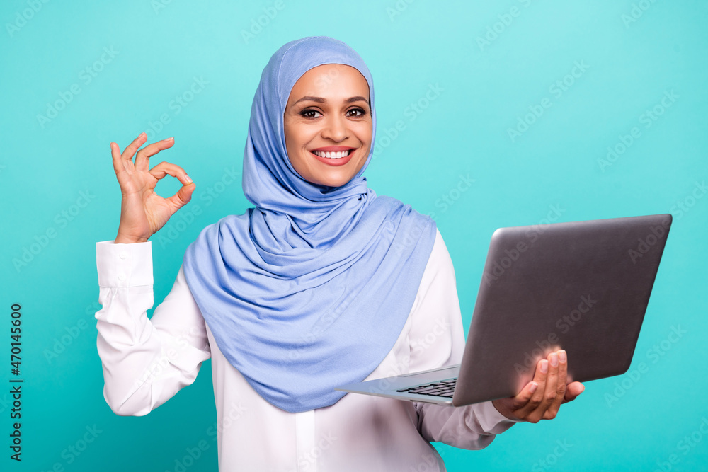 Photo of confident pretty young woman wear arab headscarf typing modern gadget showing okey isolated turquoise color background Photo of confident pretty young woman wear arab headscarf typing modern gadget showing okey isolated turquoise color background