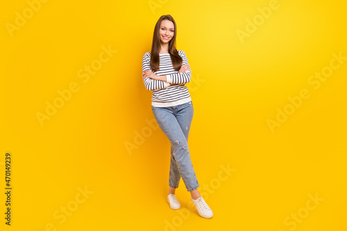 Photo of funky brunette millennial lady crossed arms wear jumper jeans sneakers isolated on yellow color background