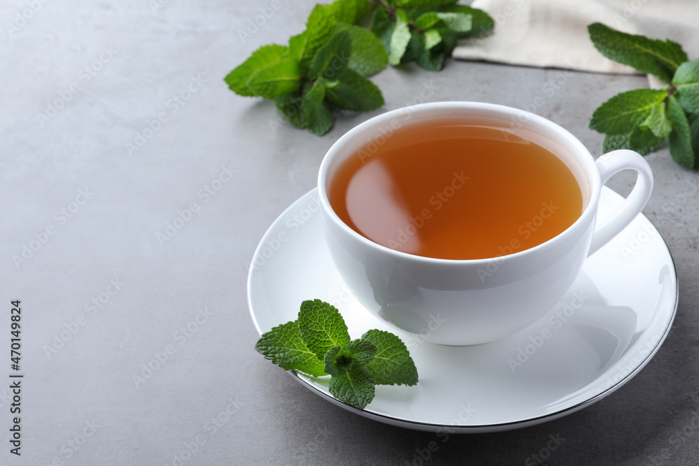 Cup of hot aromatic mint tea on light grey table. Space for text Cup of hot aromatic mint tea on light grey table. Space for text