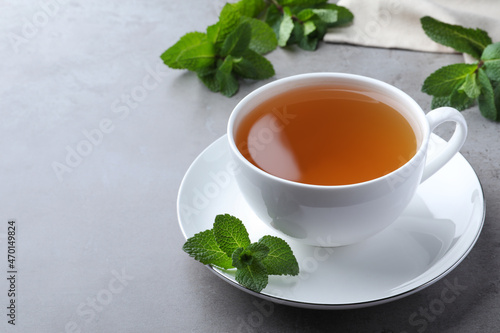 Cup of hot aromatic mint tea on light grey table. Space for text