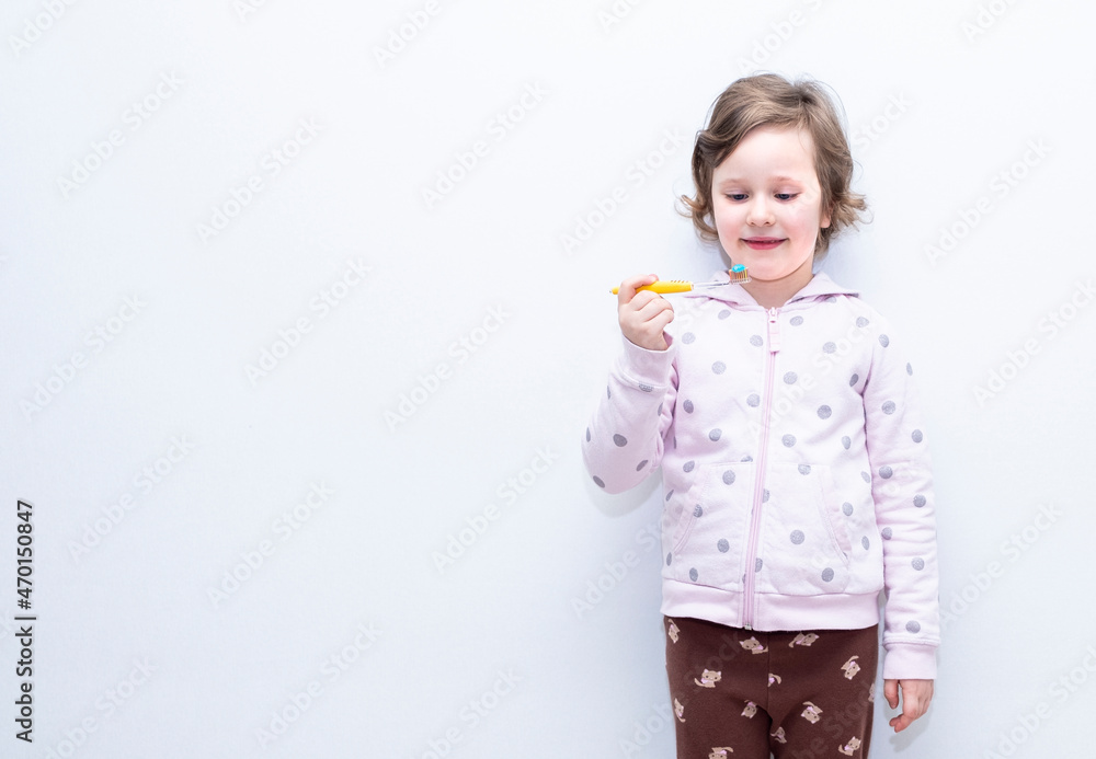 The child smiles and brushes his teeth with a toothbrush. Caucasian girl 6 years old, holding a toothbrush in her hands. The child smiles and brushes his teeth with a toothbrush. Caucasian girl 6 years old, holding a toothbrush in her hands.