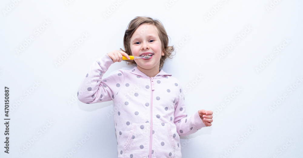 The child thoroughly brushes his teeth with a toothbrush and toothpaste. Hygiene of teeth and oral cavity. Caucasian girl on a gray background. The child thoroughly brushes his teeth with a toothbrush and toothpaste. Hygiene of teeth and oral cavity. Caucasian girl on a gray background.