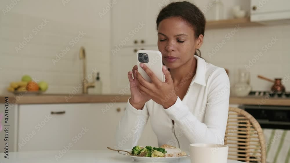 Concentrated African woman looking at the phone at breakfast Concentrated African woman looking at the phone at breakfast