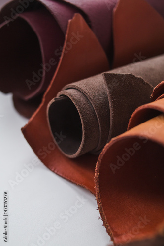 Rolls of genuine brown leather on a white background. Materials for leather goods. Manufacturing of leather goods