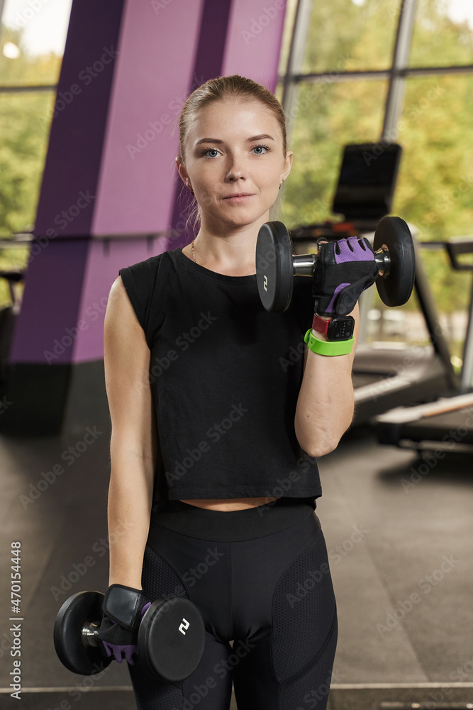 young woman shaking hands with dumbbells in the gym young woman shaking hands with dumbbells in the gym
