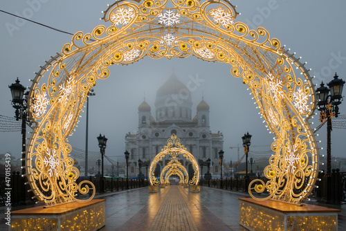 View of the white Cathedral of Christ the Saviour and the bridge with Christmas decorations on a cloudy winter. Misty winter morning in Moscow