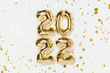 New year 2022 balloon celebration card. Gold foil helium balloon number 2022, party decoration, gold confetti stars on white background. Flat lay, merry christmas, happy holidays concept.