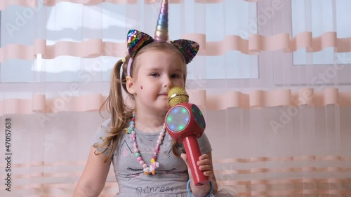 funny attractive crazy lady child singing into a karaoke microphone, with a unicorn headband, child singing karaoke music, have fun at an event future musician loud voice solo