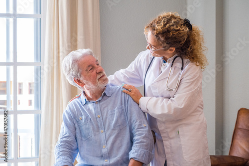 Young female doctor encouraging senior man at home. Doctor helping senior patient and giving care. Female homecaregiver taking care of retired old man. Old man and physician talking at nursing home