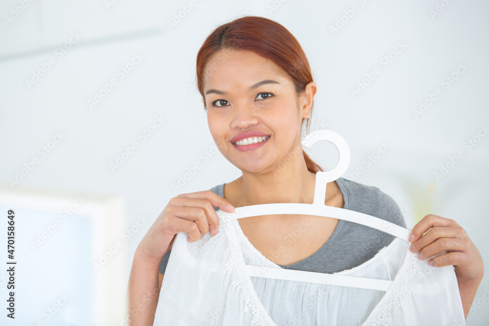 woman holding white blouse in the hanger