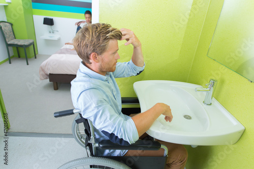 Fotografija man in wheelchair going to the toilet adapted for disable