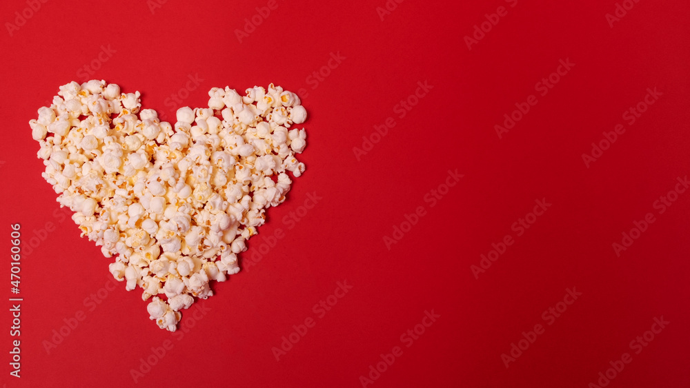 Heart-shaped popcorn on a red background with space for text. Top view. Valentine's Day, cinema time concept. Minimal style. Heart-shaped popcorn on a red background with space for text. Top view. Valentine's Day, cinema time concept. Minimal style.