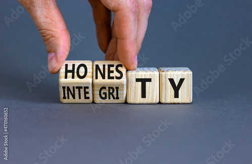 Honesty and integrity symbol. Businessman turns wooden cubes and changes the word integrity to honesty. Beautiful grey background, copy space. Business and honesty and integrity concept.