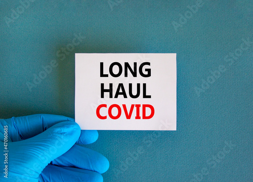 COVID-19 long-haul covid symptoms symbol. White card with words Long haul covid. Doctor hand, beautiful blue background, copy space. Medical, COVID-19 long-haul covid symptoms concept.