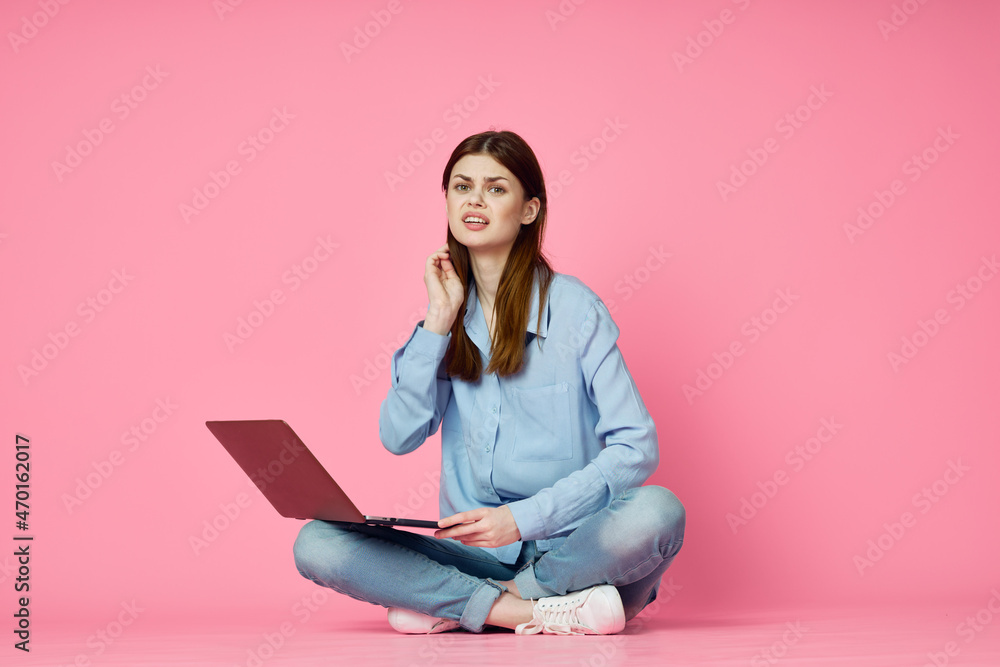 Naklejka premium woman with laptop sitting on floor technology internet shopping pink background