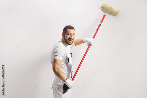 Fototapeta Naklejka Na Ścianę i Meble -  Smiling house painter painting a wall and looking at camera