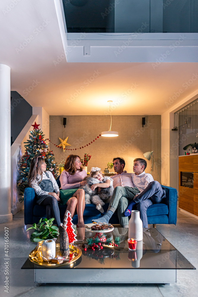 A happy family is sitting in a Christmas decorated living room