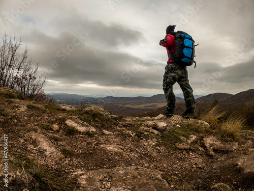 Adventure man with back pack on mountain top at cloudy day