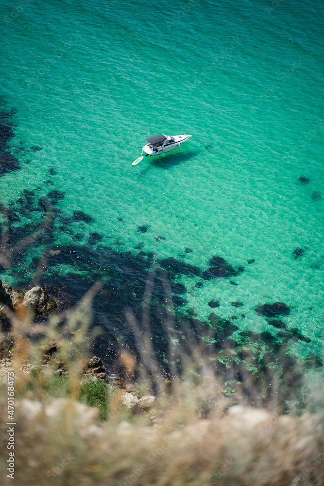 Lonely yacht boat moored in bounty lagoon, Cape Fiolent in Balaklava, Sevastopol, Russia. View from the top of the rock. Azure emerald gree sea water on sunny day. Vacation summer travel concept