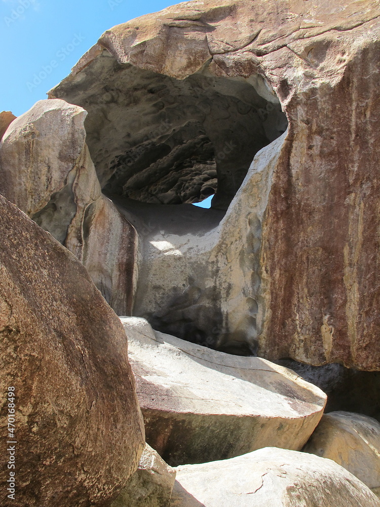 Cave or tunnel traversing a giant rock. White and rusty rocks formation ...