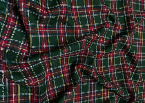 Green tartan woolen school uniform fabric material. Scottish classic seamless flannel cloth. Traditional wave pattern for a Christmas background or wallpaper. Black, Green, Red and White checkered.