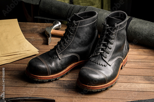 Hand crafted black leather high boots on wooden background © Hihitetlin