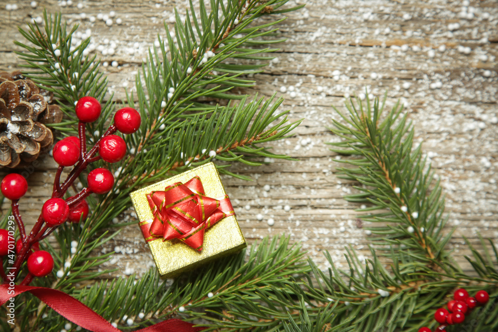 Christmas tree branches, gift box, conifer cones and red berries top view with copy space on old wooden background. Christmas, winter holiday, new year concept. Christmas tree branches, gift box, conifer cones and red berries top view with copy space on old wooden background. Christmas, winter holiday, new year concept.