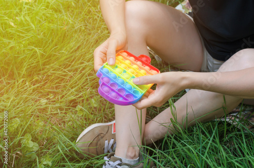 Unrecognizable woman playing with a pop it toy in nature