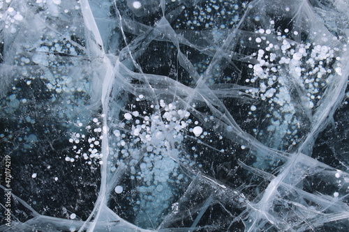 Bubbles in ice on Baikal lake in winter, snow landscape
