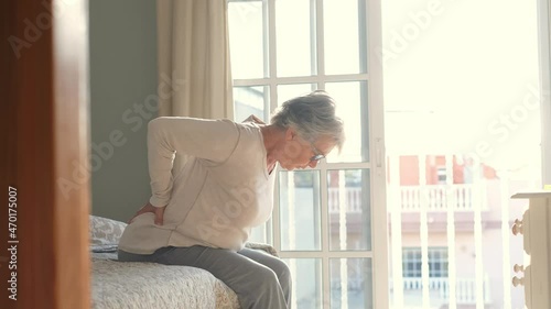 Tired senior woman suffering from backache after sleep, rubbing stiff muscles, Old female sitting on bed touching lower back feeling discomfort because of uncomfortable bed at home
 photo