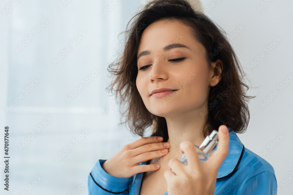 pleased young woman spraying perfume on neck. pleased young woman spraying perfume on neck.