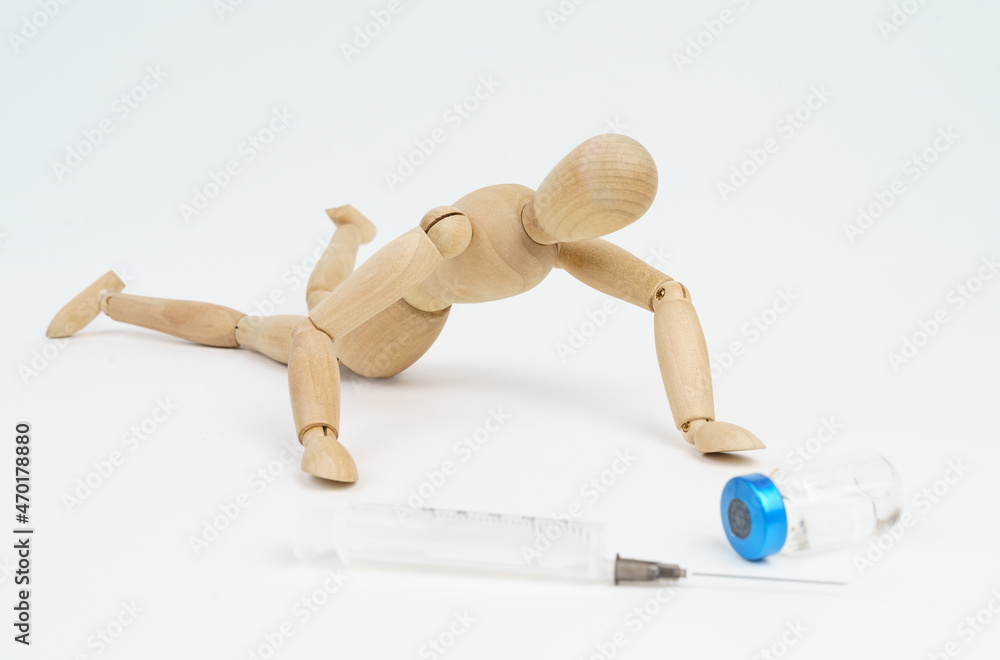The wooden man crawls towards the syringe and injection. Isolated on white background. The wooden man crawls towards the syringe and injection. Isolated on white background.