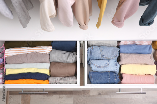 Open drawers with folded clothes indoors, top view. Vertical storage photo