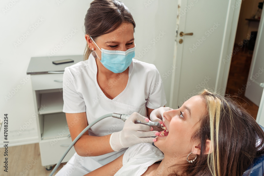 Female dentist performing a lathe treatment on an adolescent patient. Concept dental care, health care. Female dentist performing a lathe treatment on an adolescent patient. Concept dental care, health care.