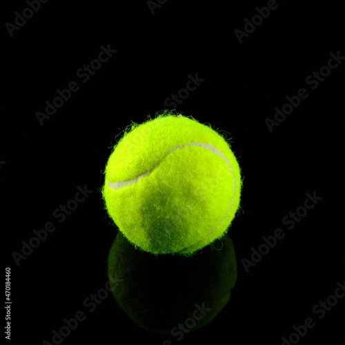 Tennis ball at black glossy surface and black background © Philipp Berezhnoy
