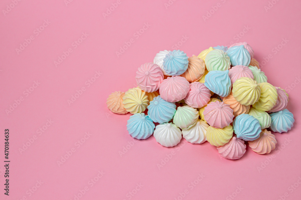 Multicolored meringues on a pink background. A pile of meringues on a bright background, there is a place for copy space Multicolored meringues on a pink background. A pile of meringues on a bright background, there is a place for copy space