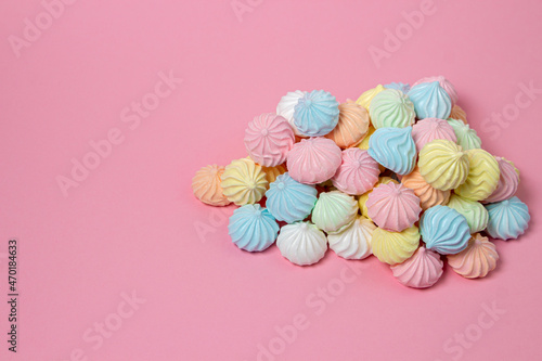 Multicolored meringues on a pink background. A pile of meringues on a bright background, there is a place for copy space