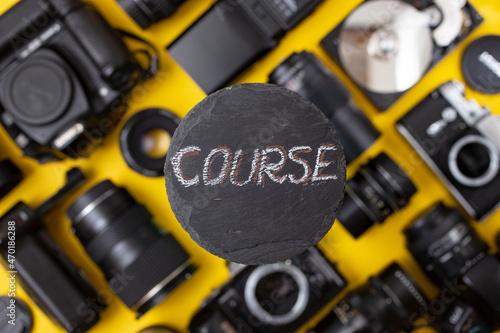 "course" written on a black stone tile, with camera gear blurred in the background